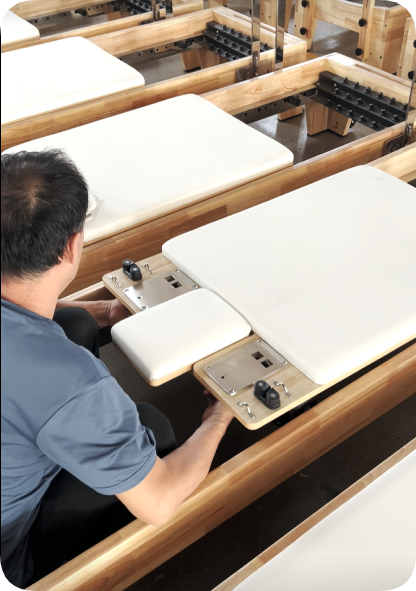 Technician completing final manual adjustment on Pilates reformers